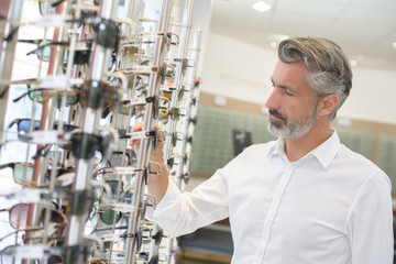 man choosing new glasses at opticians