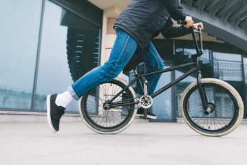 A man riding a BMX bike in the city on the background of architecture. Cycling. BMX culture