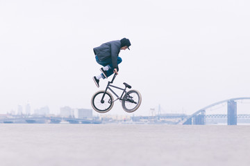 Young BMX bicycle reader does tricks in the air against the background of the urban landscape. BMX...