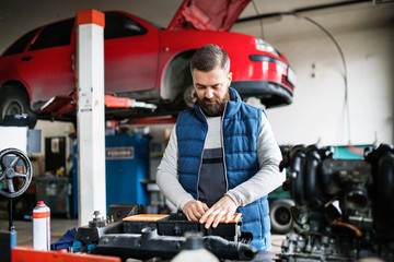 Man mechanic repairing a car in a garage.