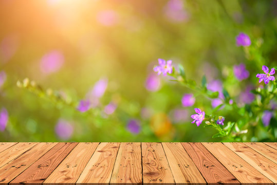 Wooden table on and blur nature  green tree and purple flower during sunset light background for spring or summer concept.