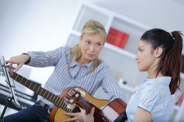 mature female teaching her student how to play guitar