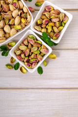 Pistachios on white wooden background with top view