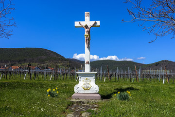 jesus cross in front of daffodils spring flowers and hambach castle in Sankt Martin, Palatinate, Germany