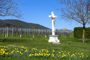 jesus cross in front of daffodils spring flowers and hambach castle in Sankt Martin, Palatinate, Germany