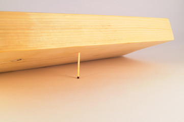 A wooden board at an angle to the surface, supported by one thin match.