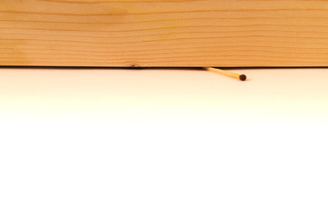 A match crushed by a wooden board, a wood texture and a white background with a splitting in the...