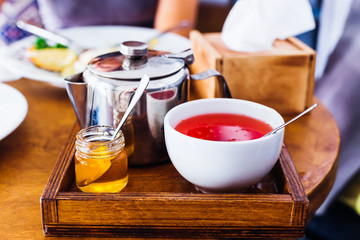 Fruit tea, honey and a metal kettle on a beautiful wooden tray