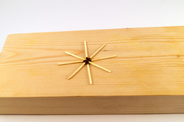 Eight thin matches laid in the form of a star on the treated surface of a wooden board.