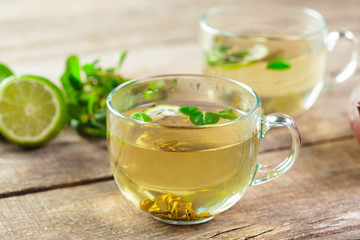 cup of black tea with mint leaves on a wooden table
