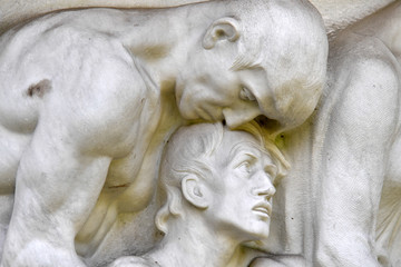 Fototapeta na wymiar A man gives comfort to another man. Part view of a relief on the old cemetery in Berlin-Stahnsdorf