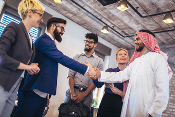 Cheerful group of business team welcoming arabian businessman