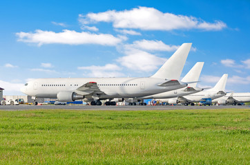 Row of passenger aircraft airplane parked at the airport, on service before departure.