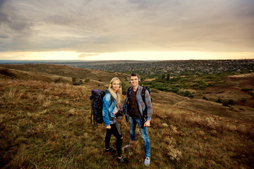 Young couple of tourists with backpacks on the nature.