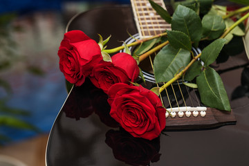 Fototapeta na wymiar Red roses on black guitar.