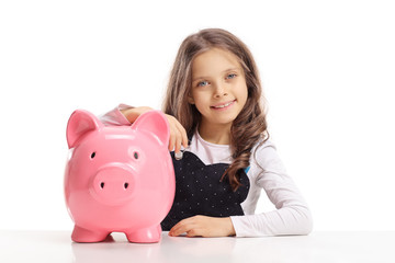 Little girl with a piggybank sitting at a table