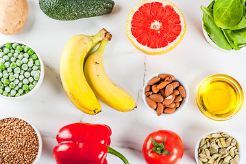 Alkaline food background, trendy Alkaline diet products - fruits, vegetables, cereals, nuts. oils, white marble background above copy space