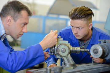 Engineer setting up equipment being watched by apprentice
