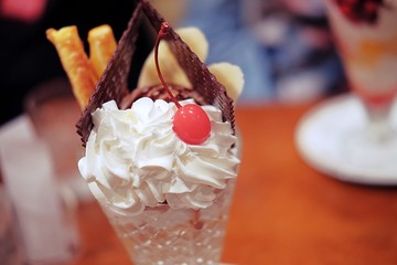 close up, a chocolate parfait served with chocolate wafer, cherry, bread stick and banana and served in a tall glass.