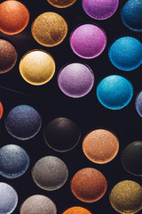 Colorful eyeshadows in rows on black background.