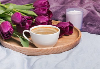 Fototapeta na wymiar Cup of coffee, tulips and candle close-up