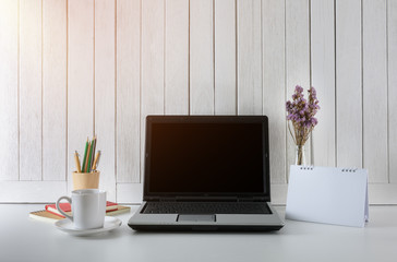 workplace background with Blank white screen modern laptop computer. White wooden vintage blackground