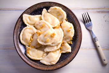 Pierogi or pyrohy, varenyky, vareniki, dumplings served with caramelized salted onion in bowl on wooden table. horizontal