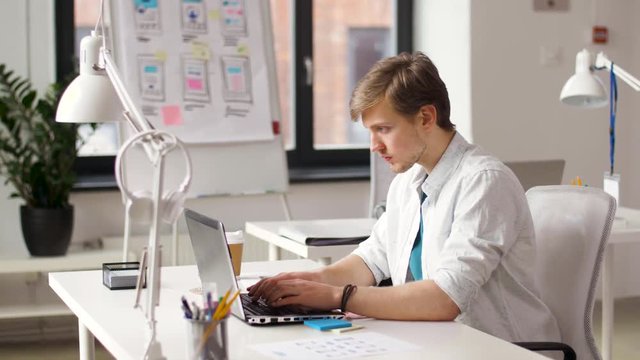 business and creative people concept - male designer or software developer with laptop computer networking at office