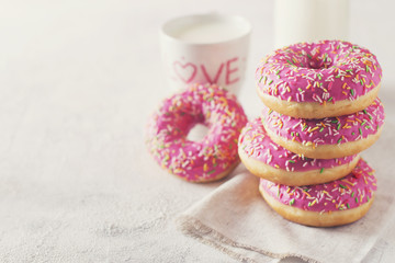 Stack of pink and white donats with bottle of milk over white background