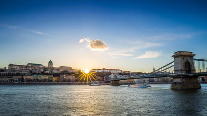 Budapest, Hungary - Sightseeing boats on River Danube at sunset with Szechenyi Chain Bridge and Buda Castle Royal Palace. Clear blue sky.