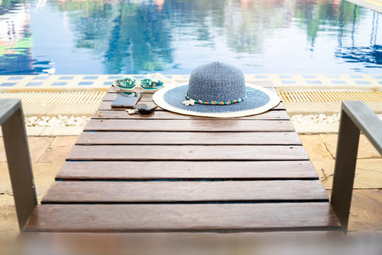 The Hat Is Placed At The Wooden Table Side The Swimming Pool With Smartphone And Goggle.