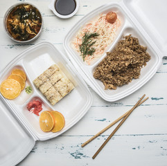 concept of Asian fast food, kimchi soup, rice with chicken, sushi rolls, soy sauce, wasabi, orange juice, on a white rustic background flat lay