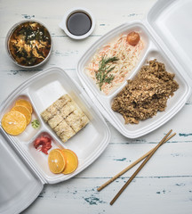 concept of Asian fast food, kimchi soup, rice with chicken, sushi rolls, soy sauce, wasabi, orange juice, on a white rustic background flat lay