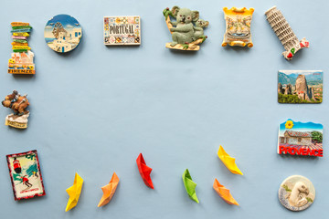  colorful paper ships and  various souvenir magnets from several world country arranged on the blue background  