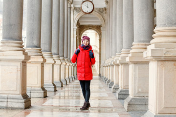 Woman tourist posing among columns in colonnade in Karlovy Vary, Czech Republic