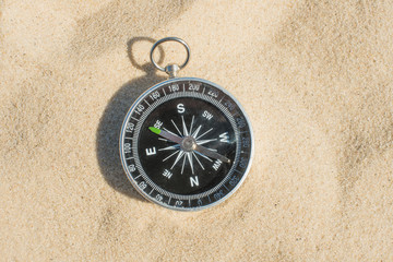 Compass buried in the sand on the beach concept of lost or direction