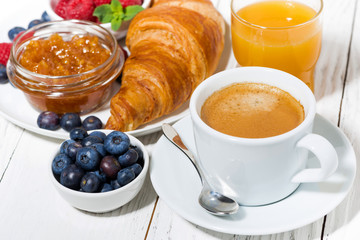 delicious breakfast with croissant and fresh berries on white wooden  table, closeup