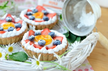 Small basket shaped tart with peaches, strawberries and cream