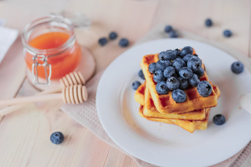Belgian waffles with blueberries on the light wooden table. Healthy breakfast. 
