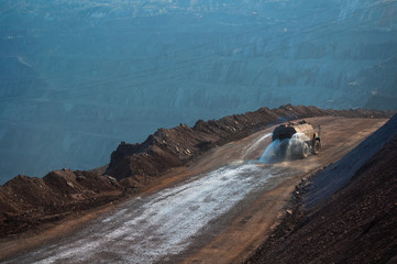 Heavy truck pours the road with water in the iron ore quarry. Dust removal, protection of the environment. Irrigation of the road from dust