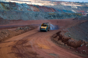 Heavy truck pours the road with water in the iron ore quarry. Dust removal, protection of the environment. Irrigation of the road from dust