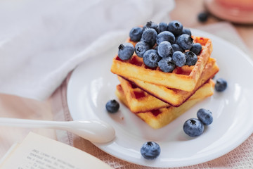 Belgian waffles with blueberries on the light wooden table. Healthy breakfast. 
