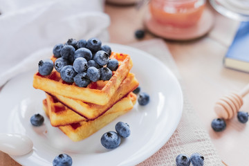 Belgian waffles with blueberries on the light wooden table. Healthy breakfast. 