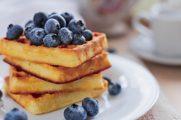 Belgian waffles with blueberries on the light wooden table. Healthy breakfast. 