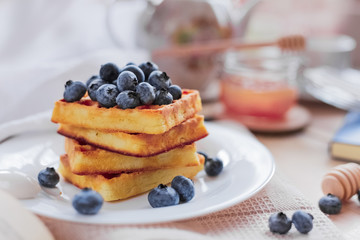 Belgian waffles with blueberries on the light wooden table. Healthy breakfast. 