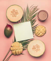 healthy food, melon, mango and smoothies are laid out on a tropical leaf, with a postcard and space for text, on a pink background, space for text flat lay