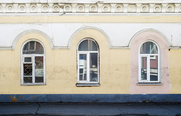Three windows of an ancient building. Fragment of the facade. The picture was taken in Russia, in the city of Orenburg. 04/07/2018
