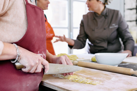 Preparation of fresh tagliatelle by cutting pasta dought with knife during cooking class