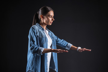 Interesting experience. Pleasant nice young woman holding her hands in front of her and looking at them while enjoying modern technology