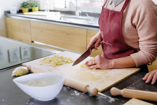 Preparation of fresh tagliatelle by cutting pasta dought with knife during cooking class